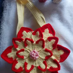 A detailed shot of the Lotus Bag against a soft background, with some crochet roses to complement the floral theme.