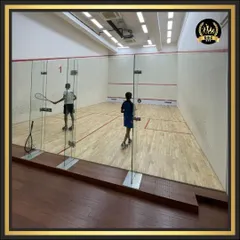 Two players engaged in a fast-paced game of squash, viewed from behind the glass wall. Our courts provide an excellent viewing experience for spectators.