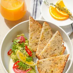 A true crowd-pleaser, our Smashed Chilli and Avocado Toast is breakfast perfection. We serve it on our house-made multigrain bread with a zesty topping of fresh avocado, red chilli, and lemon, paired with a glass of freshly squeezed orange juice.