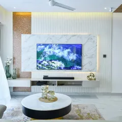 This sleek TV unit is set against a marble-clad wall, glowing with soft backlighting. Warm metallic accents and textured details create a look that is simple, modern, and perfectly put together.
