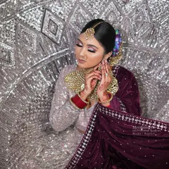 An elegant side profile showcasing the floral hair accessory and the neatness of the bridal updo, set against a shimmering backdrop.