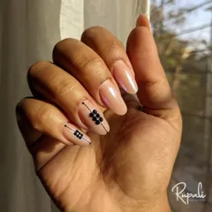 A modern design on a pearlescent nude base. I used black studs and fine lines to create a geometric accent on two nails.