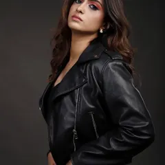 A model in a black leather jacket and jeans, captured in a classic three-quarter portrait against a grey studio background. This is a staple look for a versatile model portfolio.