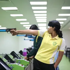 A young athlete takes aim with a pistol at our indoor shooting range. We provide a safe and professional environment for shooters to develop the focus and precision required for their sport.