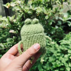 A hand-held shot of the frog AirPods case, showing its size and adorable little face.