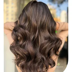 This is the glow-up you've been dreaming of. We created these dazzling warm brown highlights, styled into soft, luxurious waves that catch the light perfectly. This look brings incredible life and dimension to brunette hair.