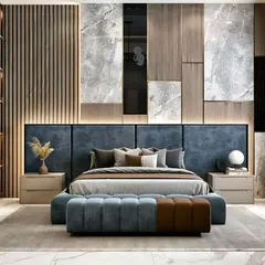 A luxurious bedroom design showcasing a mix of materials. The back wall features wood fluting, grey marble panels, and a large upholstered headboard, creating a rich, textured backdrop for the room.