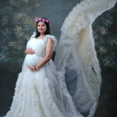 A vision in white. This stunning portrait showcases a designer maternity gown with a dramatic ruffled train, making the mother-to-be look and feel like royalty.