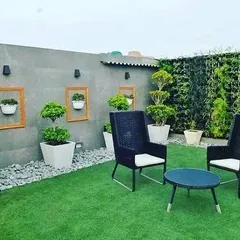 This modern terrace features a combination of elements: a vertical garden for privacy, framed planters as wall art, and a comfortable seating area on an artificial lawn.