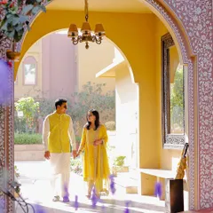 A moment of quiet connection, framed by a sunlit archway of a palace. The warm tones and architectural details add a layer of royalty to this candid couple portrait.
