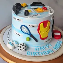 This cake was designed for a colleague's birthday, covered in all his favorite things. This view shows his love for tennis, Figma, and inside jokes like "Gossip" and "Arey."