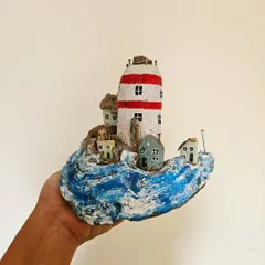 A still shot capturing the rustic charm of "The Crowded Shore" sculpture. Each tiny house is crafted and placed to create a sense of a bustling seaside village, all balanced on a natural wave of driftwood.