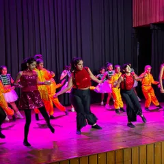 A wide shot of a group performance during our 2024 recital. The combination of different age groups, vibrant costumes, and professional stage lighting creates a truly magical experience for both performers and the audience.