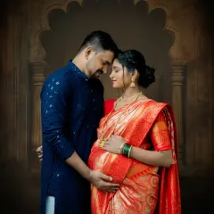 An intimate couple's portrait from a traditional maternity session. The focus is on their connection, with both partners embracing the baby bump, set against a classic arched backdrop.