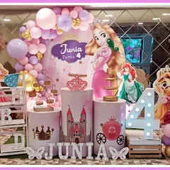 A grand princess-themed fourth birthday party. This setup features cutouts of various Disney princesses like Rapunzel and Ariel, a castle-themed backdrop, and a large light-up number '4'.