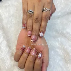 This beautiful set on natural nails features a reddish-pink ombré with gold flakes and delicate, hand-sculpted 3D flowers. It's a very intricate and feminine design.