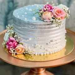 A stunning silver-dusted tall cake for a 25th wedding anniversary. The metallic sheen combined with fresh flowers and delicate pearls creates a sophisticated and celebratory feel.