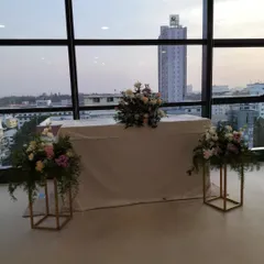 A simple and professional setup for a corporate office event. The floral arrangements are elegant and understated, complementing the modern office space with a city view.