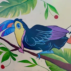 A close-up of the finished toucan, highlighting the bright blue beak and purple wing details against the green foliage.