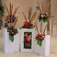 An artistic floral installation on modern white pedestals. I used red roses, pampas grass, and monstera leaves to create these unique arrangements, which can be used to define a space or as standalone decor pieces.