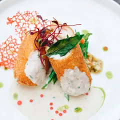 This beautifully plated dish is all about fine dining. The bright, clean lighting and careful composition highlight the chef's artistry, from the crispy texture of the roll to the delicate sauce work.