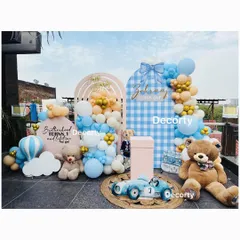 A charming teddy bear party setup on a rooftop. This "Brotherhood" theme for a joint birthday uses a blue and tan color palette with a cute gingham-patterned backdrop.