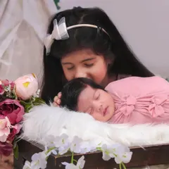 A tender moment as a big sister gently kisses her sleeping newborn sibling. These are the precious memories I love to capture for families.