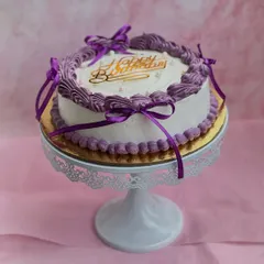 Vintage vibes and violet dreams! This beautiful birthday cake features delicate purple buttercream piping and is tied with satin ribbons for a classic, elegant look.