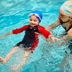 Safety and trust are the foundation of our teaching. Here, one of our certified coaches provides hands-on support, helping a young swimmer learn to float and feel secure in the water.