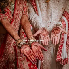 The groom's mehendi is part of the story too. Here, the bride's hands feature intricate patterns, while the groom's palms hold a custom monogram and a small Ganesha motif for blessings.