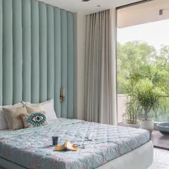 Featured in Architecture+Design magazine, this view of the master bedroom highlights the channel tufted headboard in a calming blue. The design intentionally draws the eye towards the balcony and the green canopy beyond, emphasizing the indoor outdoor connection.