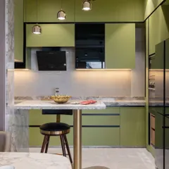 The breakfast bar, with its marble top and brass-finished support, serves as a beautiful transition between the kitchen and the living space. It’s perfect for quick meals or a morning cup of coffee.