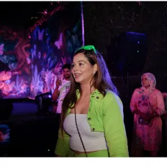 A smile on my face as I watch the crowd enjoy the neon party I'm hosting.