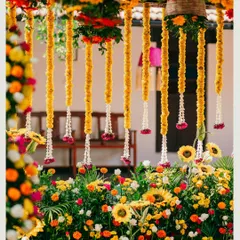 A close-up of the Haldi decor, featuring hanging marigold strings and a bed of sunflowers. We focus on layering different flowers and textures to create a rich, traditional look.