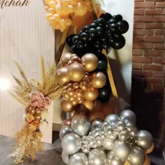 This close-up shows the detail of the organic balloon garland. I used a sophisticated colour palette of chrome gold, silver, black, and peach to complement the rustic brick wall and dried floral elements.