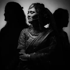 This black and white portrait uses silhouettes to create a powerful, artistic image. The focus is on the bride, flanked by shadows, symbolizing her journey and the important people in her life.