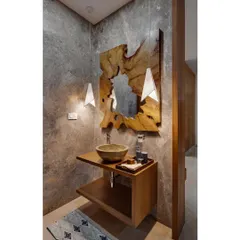 The powder room in the Nataraj House features a live-edge wood mirror and a stone-finish sink, set against a textured cement wall. This combination of raw, natural materials creates a grounded and sophisticated space.