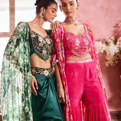 Two models showcasing vibrant festive wear. The makeup for both is kept cohesive with an emphasis on defined eyes and a warm, peachy blush that complements both the pink and green outfits.