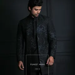 I designed this midnight-black achkan for the man who appreciates understated elegance. The slim, knee-length silhouette features a unique lattice texture and subtle ink-blue ornamental embroidery, creating a modern yet powerful statement for any evening affair.