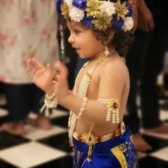 A child dressed as little Krishna, clapping and dancing. I focus on these moments of uninhibited joy, letting the child's personality shine through in a relaxed environment.