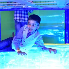 A boy having a great time on the illuminated floor panel, a unique sensory feature in our play area.