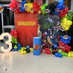 An action-packed Avengers superhero theme for a 3rd birthday. This setup includes a comic-style backdrop, character logos, and a vibrant red, blue, yellow, and black balloon garland.