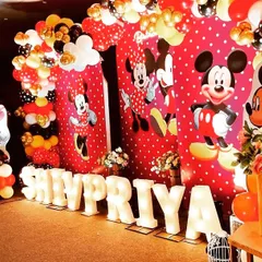 A fun and festive Mickey and Minnie Mouse themed birthday party for Shivpriya. The backdrop features the iconic characters, surrounded by a balloon arch in the classic red, yellow, and black color scheme.