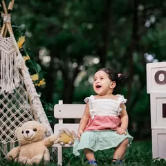 A candid moment of pure joy during an outdoor first birthday shoot. The natural background adds a beautiful, soft touch.