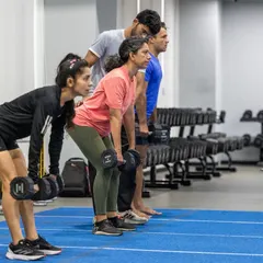A group of runners performs dumbbell rows, focusing on building upper body and back strength to maintain good posture and form during long runs.