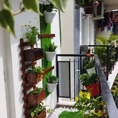 A closer look at the vertical garden setup, which combines wooden boxes and white pots on an artificial grass panel, perfect for growing herbs and flowers in a small space.