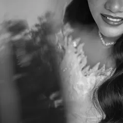 A close-up black and white shot of the bride's smile and the delicate lace of her wedding gown. This intimate detail shot captures her joy and the beauty of her bridal look.