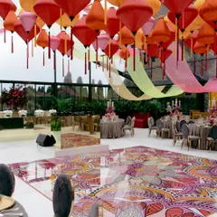 A vibrant, custom printed dance floor and a ceiling of colourful lanterns for a sangeet in Tuscany. This shows how we use bespoke design elements to create a specific theme and atmosphere, even in a clear marquee.