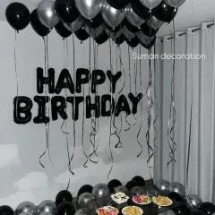 A simple birthday setup with black and silver balloons on the ceiling and floor, complemented by black "Happy Birthday" foil letters on the wall.