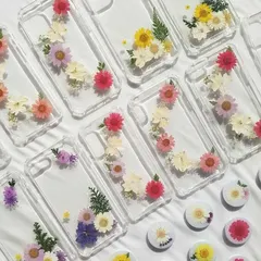 A beautiful collection of custom resin phone cases, each decorated with a unique arrangement of real dried flowers.